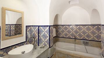 Een badkamer met een wit wastafelmeubel, een bad en blauw betegelde wanden.