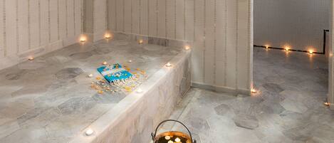 A spa room with a stone bathtub, decorative fish tiles, and a hanging light fixture.