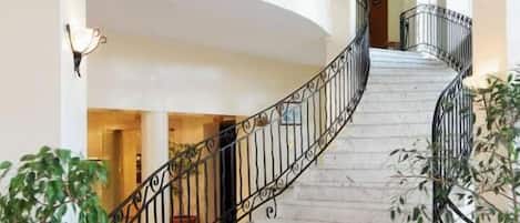 A marble staircase with black railings leading to a second floor.