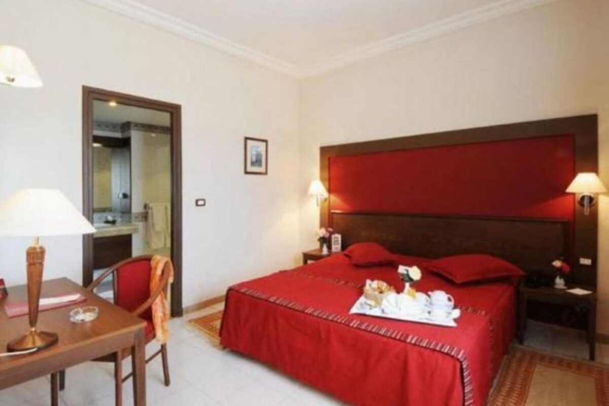 A hotel room with a bed, bedside tables, a desk, and a chair.