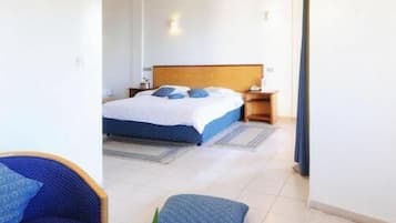 Ein Hotelzimmer mit einem Bett, einer Sitzecke mit Tisch und Blick auf das Nachbarzimmer.