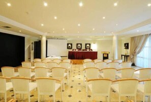 A conference room with rows of chairs, a stage with a red backdrop, and a projector screen. - Hotel du Parc (Tunis)