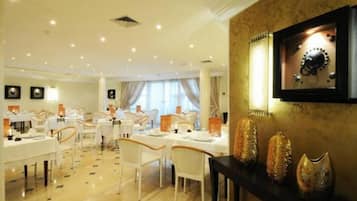 A dining area with tables set for service, a chandelier, and decorative vases.