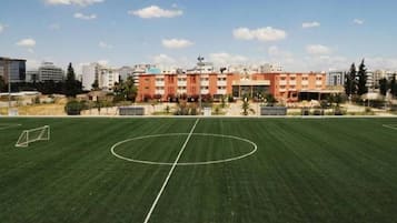 Un terrain de sport avec des poteaux de but et, au fond, un bâtiment à plusieurs étages.