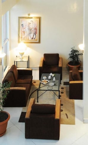 A living room with a sofa, armchairs, a coffee table, and a painting on the wall. - Hotel du Parc (Tunis)