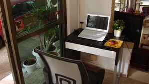 A workspace with a laptop on a desk, a chair, and a potted plant. - Hotel Rachel (Aegina)