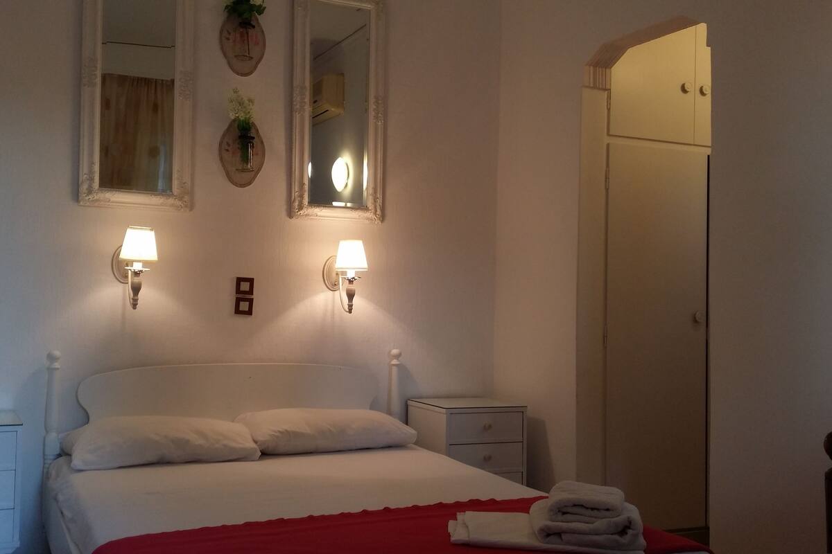 A bedroom with a bed, two bedside tables, a nightstand, a mirror, and a wardrobe.