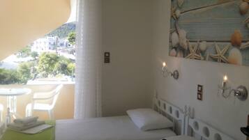 Um quarto com uma cama, uma mesinha com cadeiras e vista para a cidade através de uma janela.