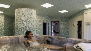 Spa-alue, jossa on suuri poreallas, laatoitetut seinät ja laatoitettu katto.