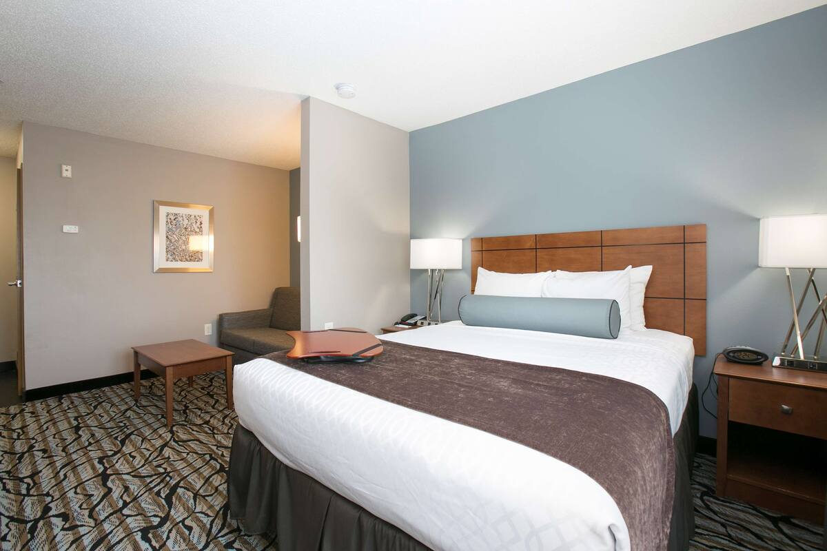 A hotel room with a large bed, two bedside tables, a desk, and a chair.