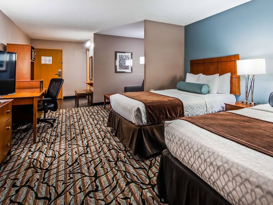 Een hotelkamer met twee bedden, een bureau, een stoel, een televisie en een kamerbreed tapijt met dessin.