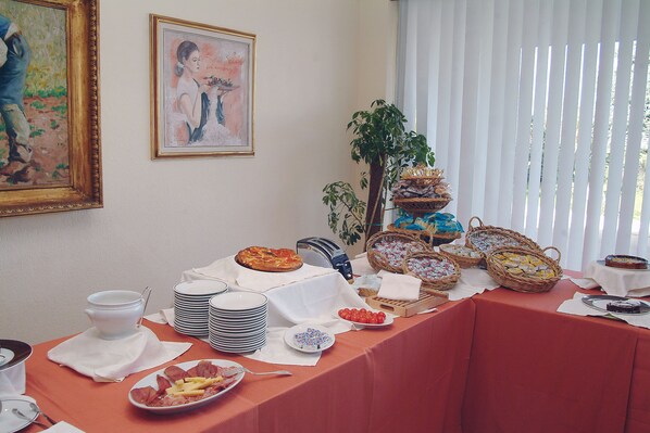 Una mesa de buffet con diversos alimentos y un cuadro en la pared.