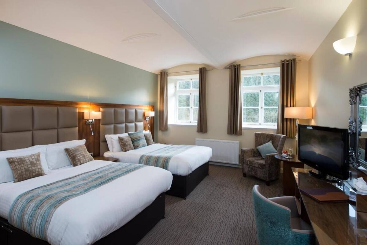 A hotel room with two beds, a television, a desk, and a chair.