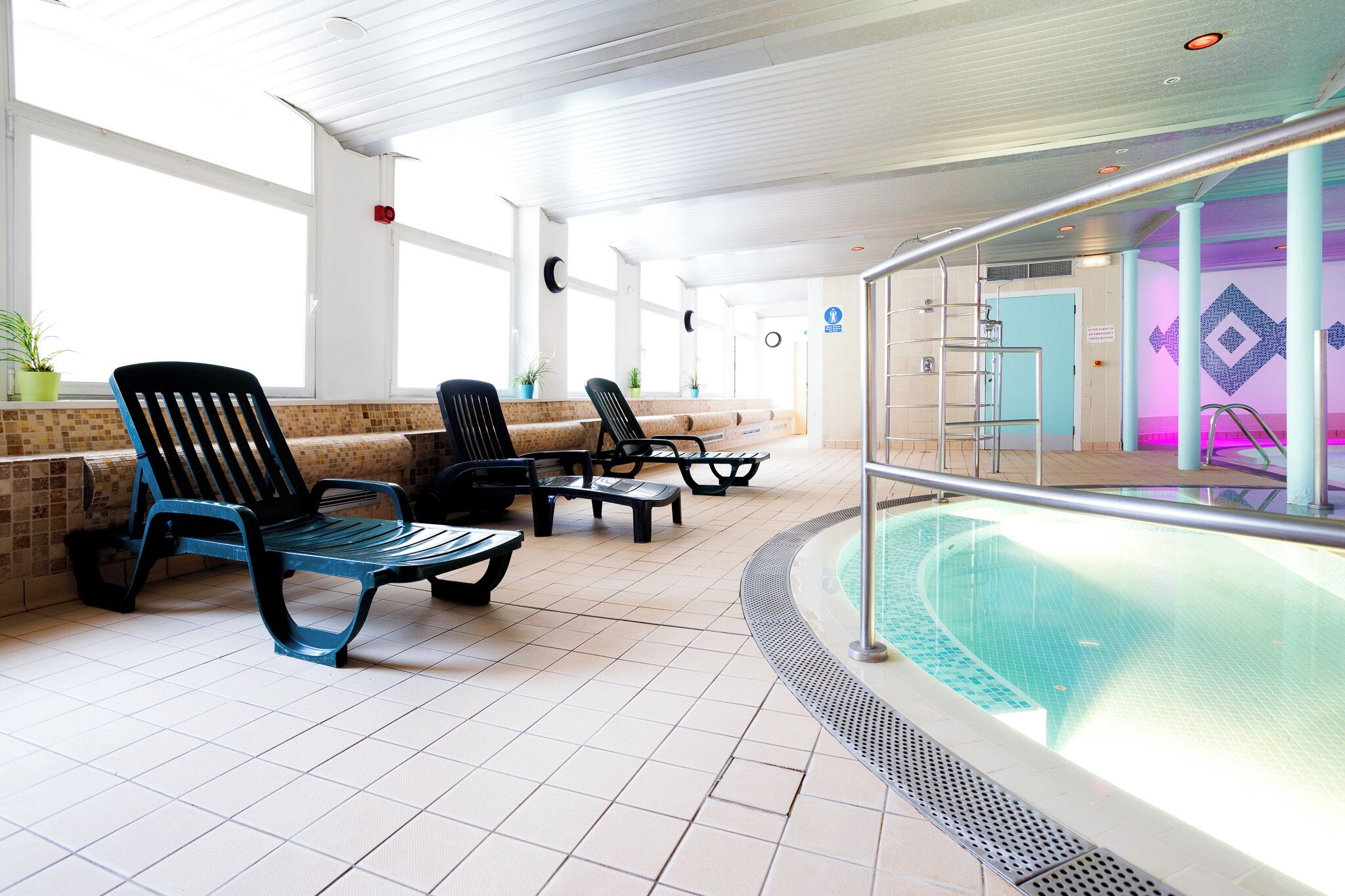 Ein Poolbereich mit Liegestühlen, einem Pool und einem gefliesten Boden.