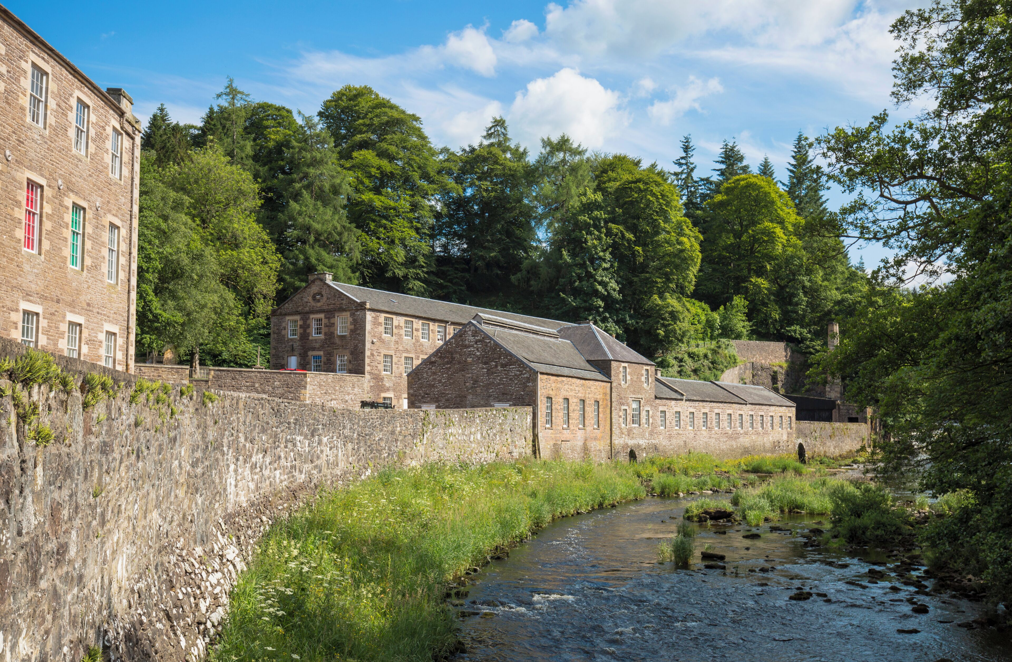 A historic stone building with multiple windows and a stone wall.