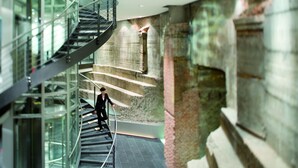 A modern interior with a spiral staircase, glass railings, and a stone wall. - Mövenpick Hotel Hamburg (Hamburg)