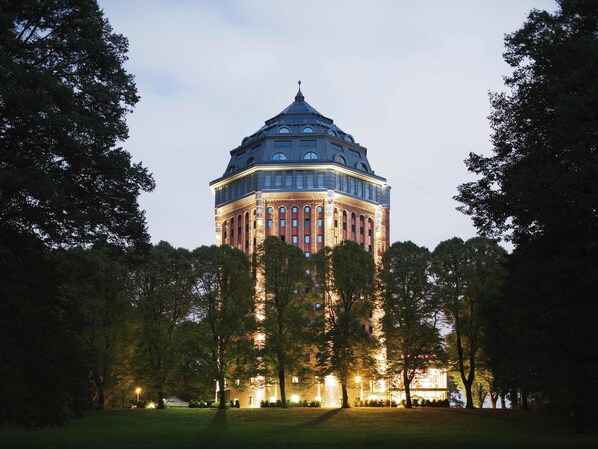 A large, multi-story building with a prominent dome and a symmetrical facade, surrounded by a well-maintained lawn and trees. - Mövenpick Hotel Hamburg (Hamburg)