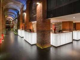 Eine moderne Hotelhalle mit Ziegelwänden, einer hohen Decke und einem zentralen Empfangsbereich.