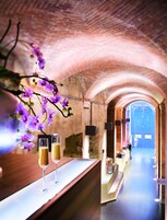 Eine Bar mit zwei Biergläsern, einer Vase mit violetten Blumen und einer Ziegeldecke.