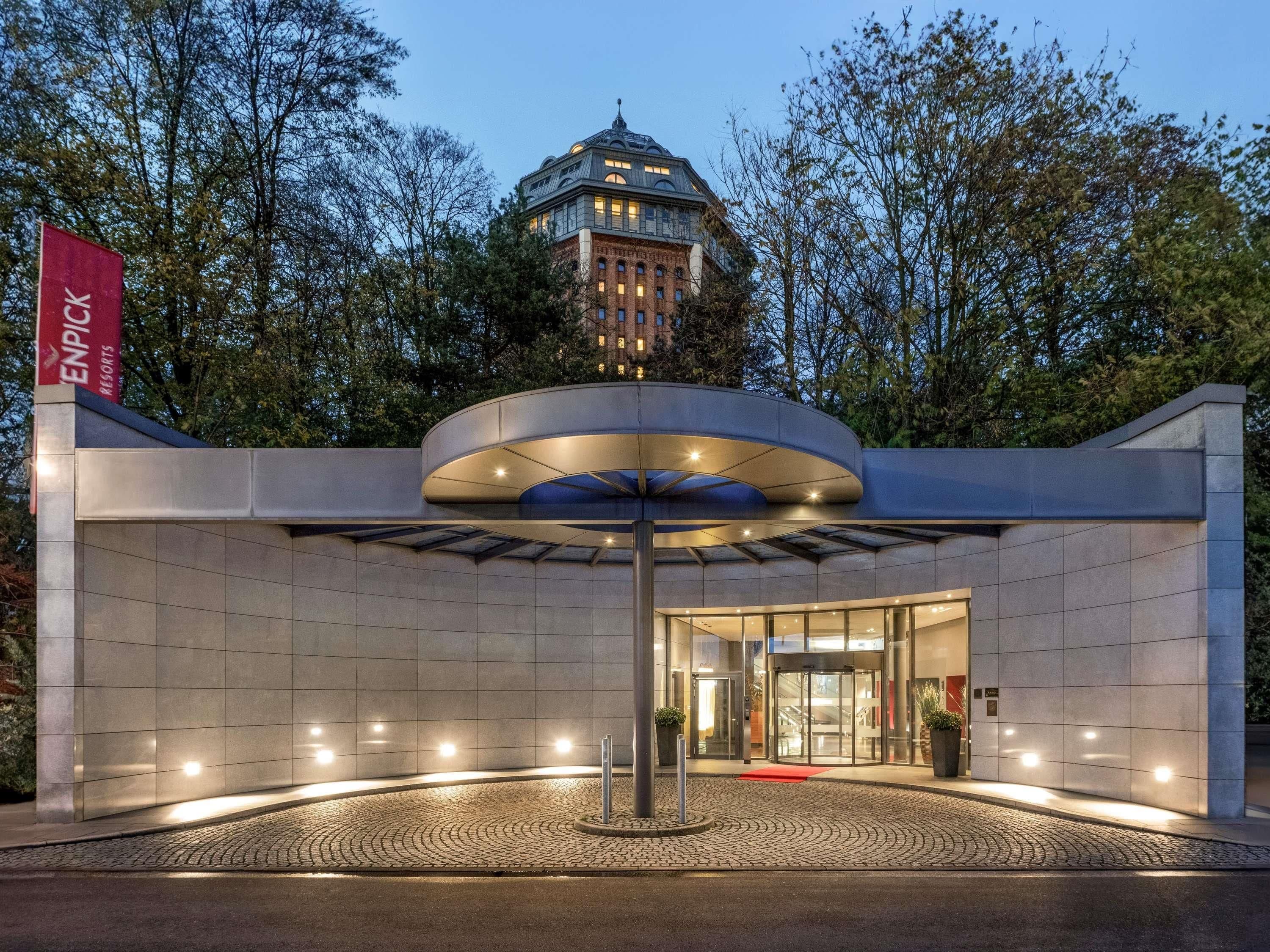 Ein moderner Hotelzugang mit Glasfassade, rotem Teppich und einer Flagge, die es als Enpicck Resort kennzeichnet.