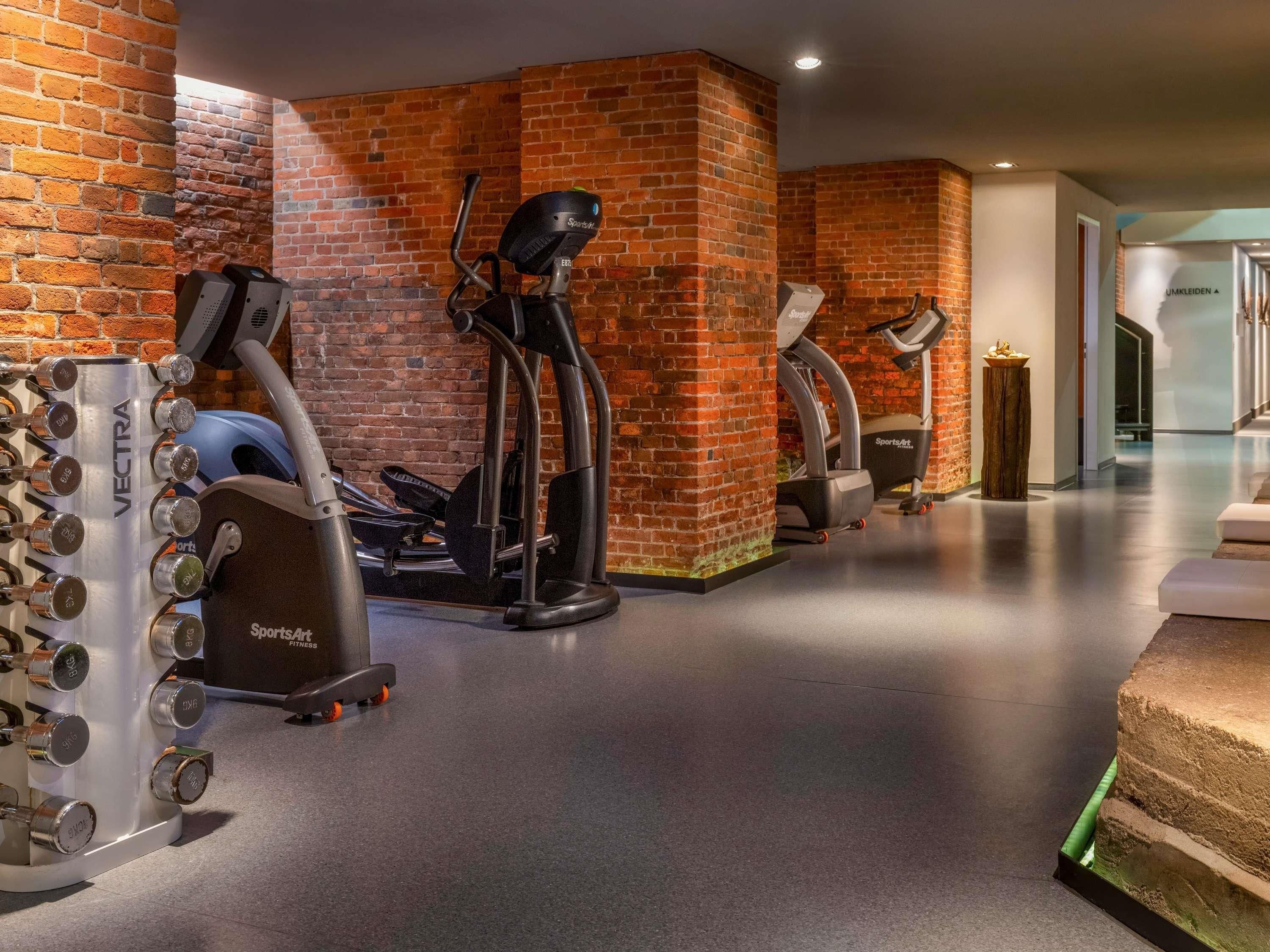 Un gimnasio con paredes de ladrillo, máquinas de cardio y equipo de pesas.