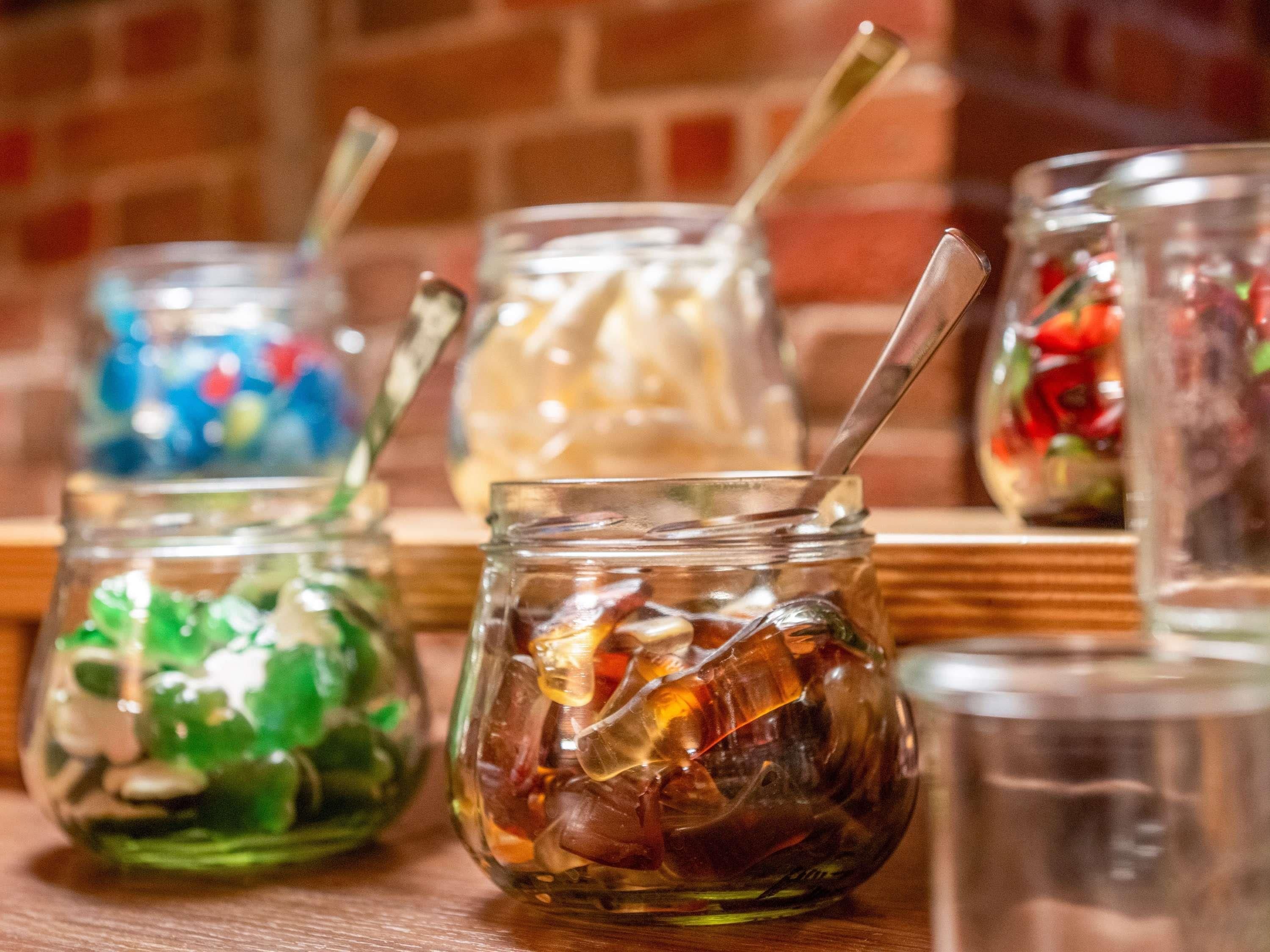 A row of glass jars with various contents on a wooden shelf.