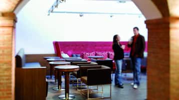 A modern interior with a pink sofa, round tables, and a brick archway.