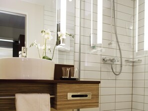 Une salle de bain moderne avec un grand lavabo blanc, un meuble-lavabo en bois, une cabine de douche en verre et un miroir au-dessus du lavabo.