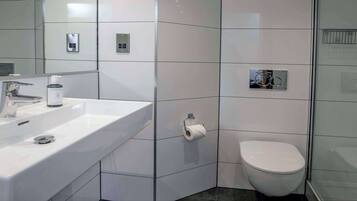A modern bathroom with a white sink, a toilet, and a shower area.