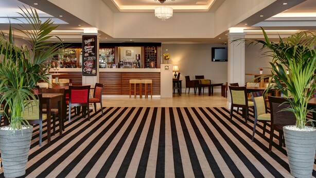 A hotel lobby with a striped carpet, a bar area, and seating arrangements. - Best Western Appleby Park Hotel (Swadlincote)