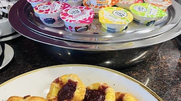 Una bandeja con vasos de yogur y un plato de pasteles.