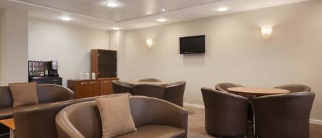 A modern lounge area with leather sofas, a wooden coffee table, and a television mounted on the wall.