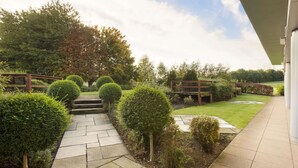 A landscaped garden with a stone pathway leading to a wooden bridge. - Ramada Plaza by WyndhamWrexham (Wrexham)