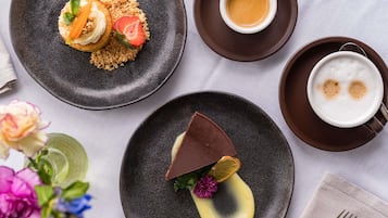 Una mesa con un plato de postre, una taza de café y un dulce de chocolate.