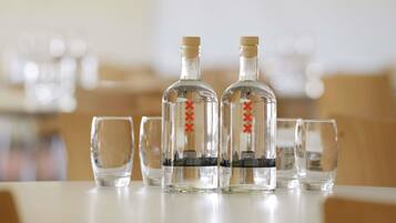 Three clear glass bottles with red markings on a table, accompanied by four empty glasses.