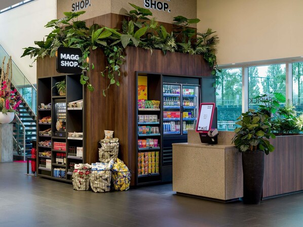 A shop with a wooden facade, shelves stocked with snacks and beverages, and a sign indicating a press-to-pay service.