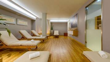 A spa room with wooden floors, white lounge chairs, and a wooden bench.