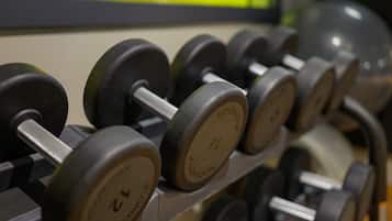 Estante con mancuernas, con indicaciones de peso, mostrando un gimnasio.