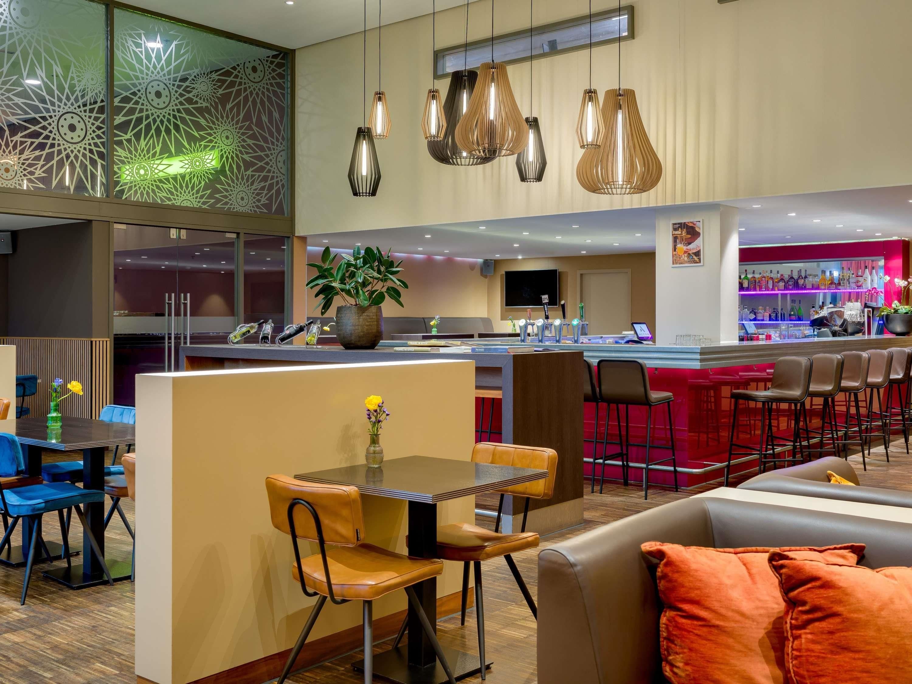 Un bar moderno con barra, asientos e iluminación decorativa.