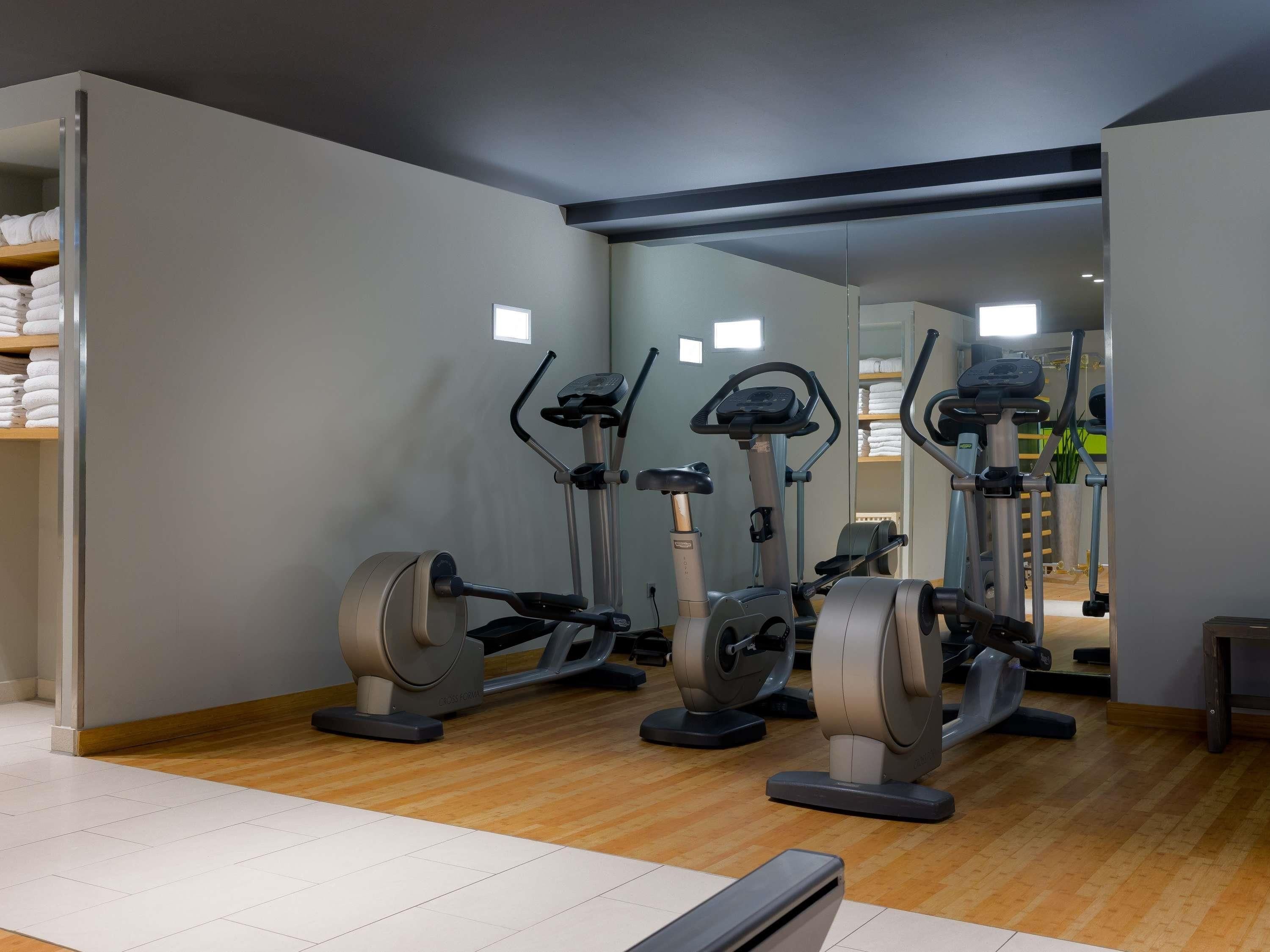 Un gimnasio con bicicletas estáticas, un espejo grande y suelo de madera.