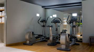 Un gimnasio con bicicletas estáticas, un espejo grande y suelo de madera.