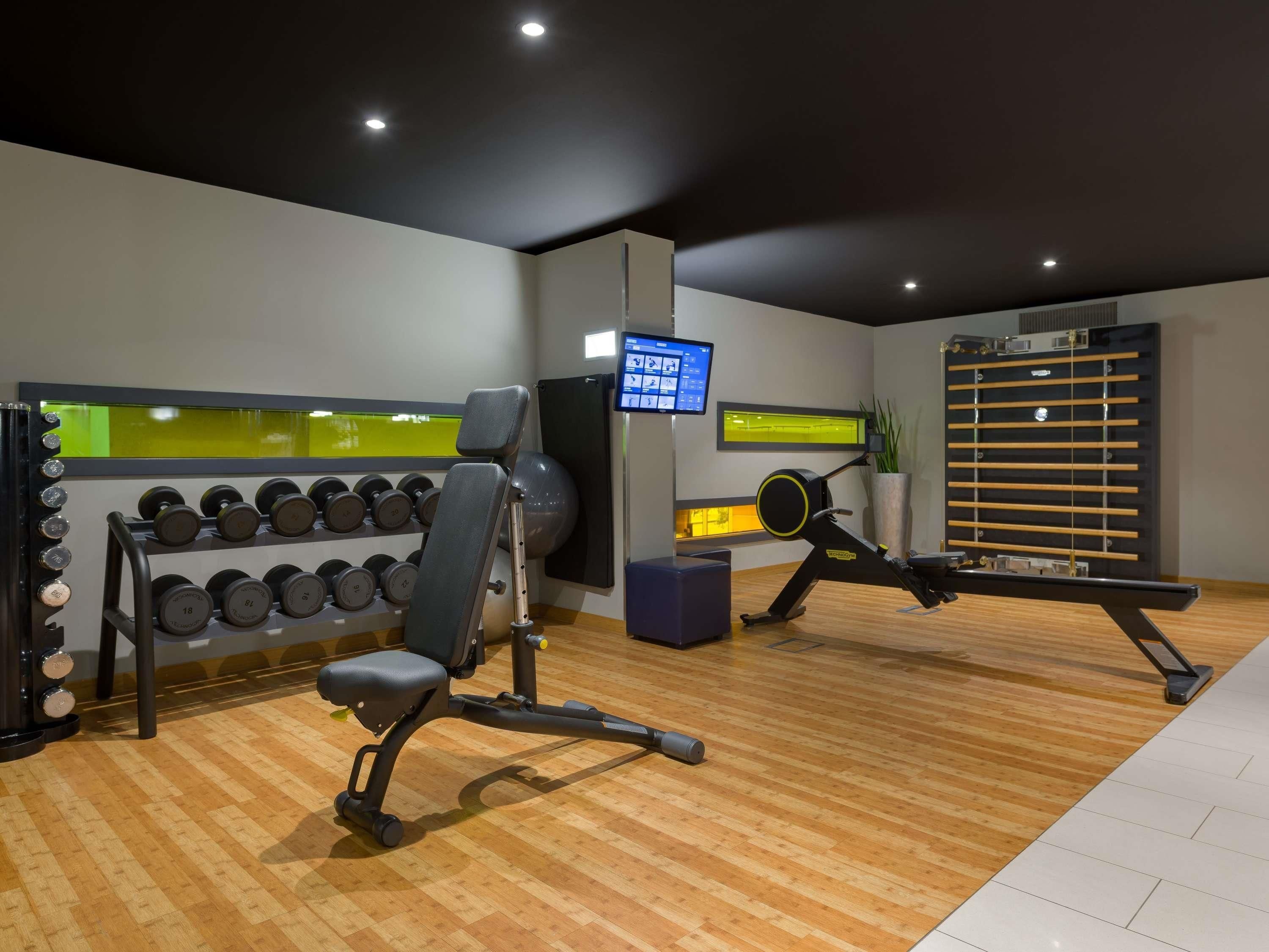 Une salle de sport équipée de matériel d’exercice, d’un téléviseur fixé au mur et d’une fenêtre donnant sur un beau paysage.