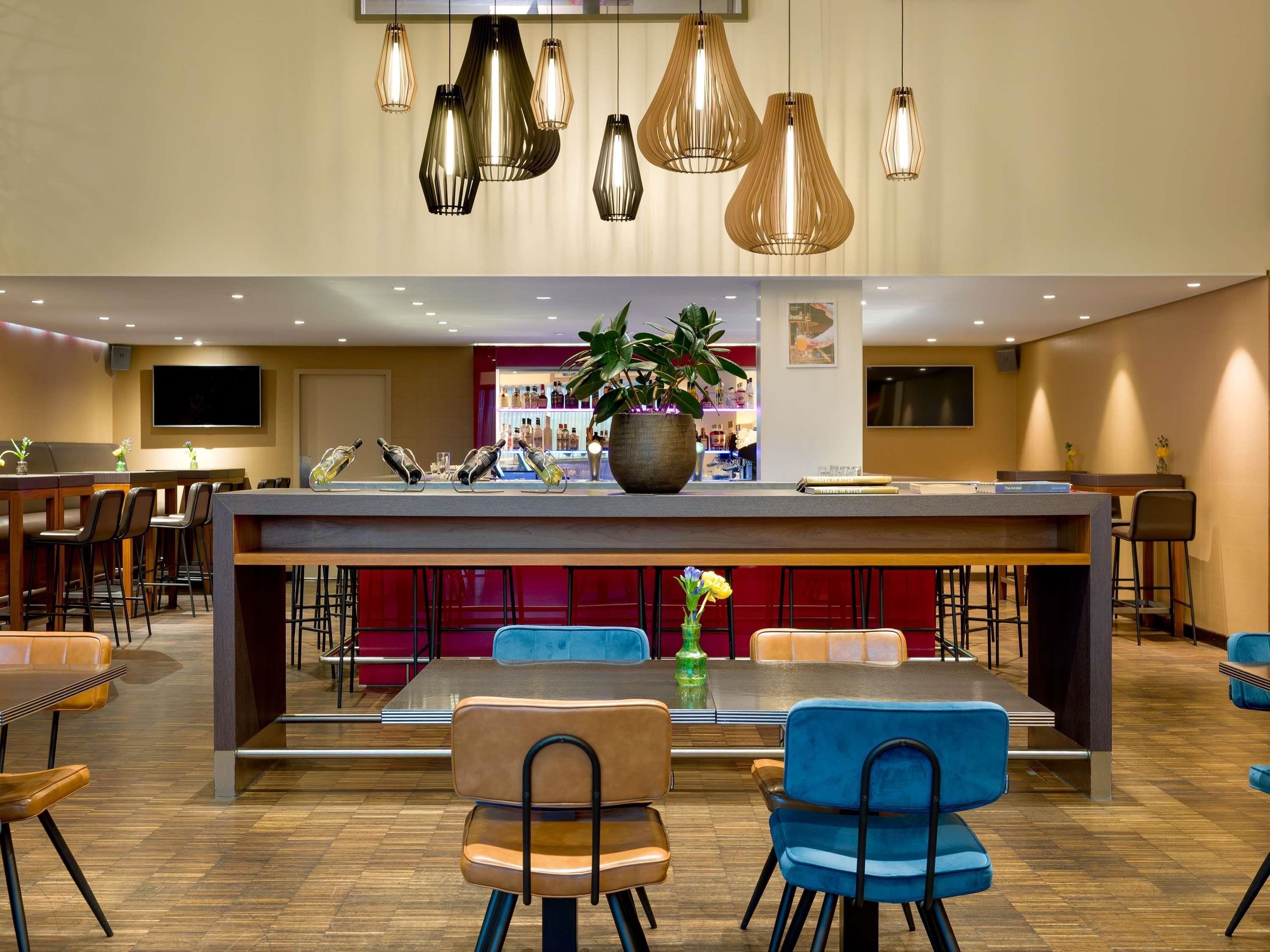 Eine moderne Hotelhalle mit einer zentralen Bar, Sitzgelegenheiten und dekorativer Beleuchtung.