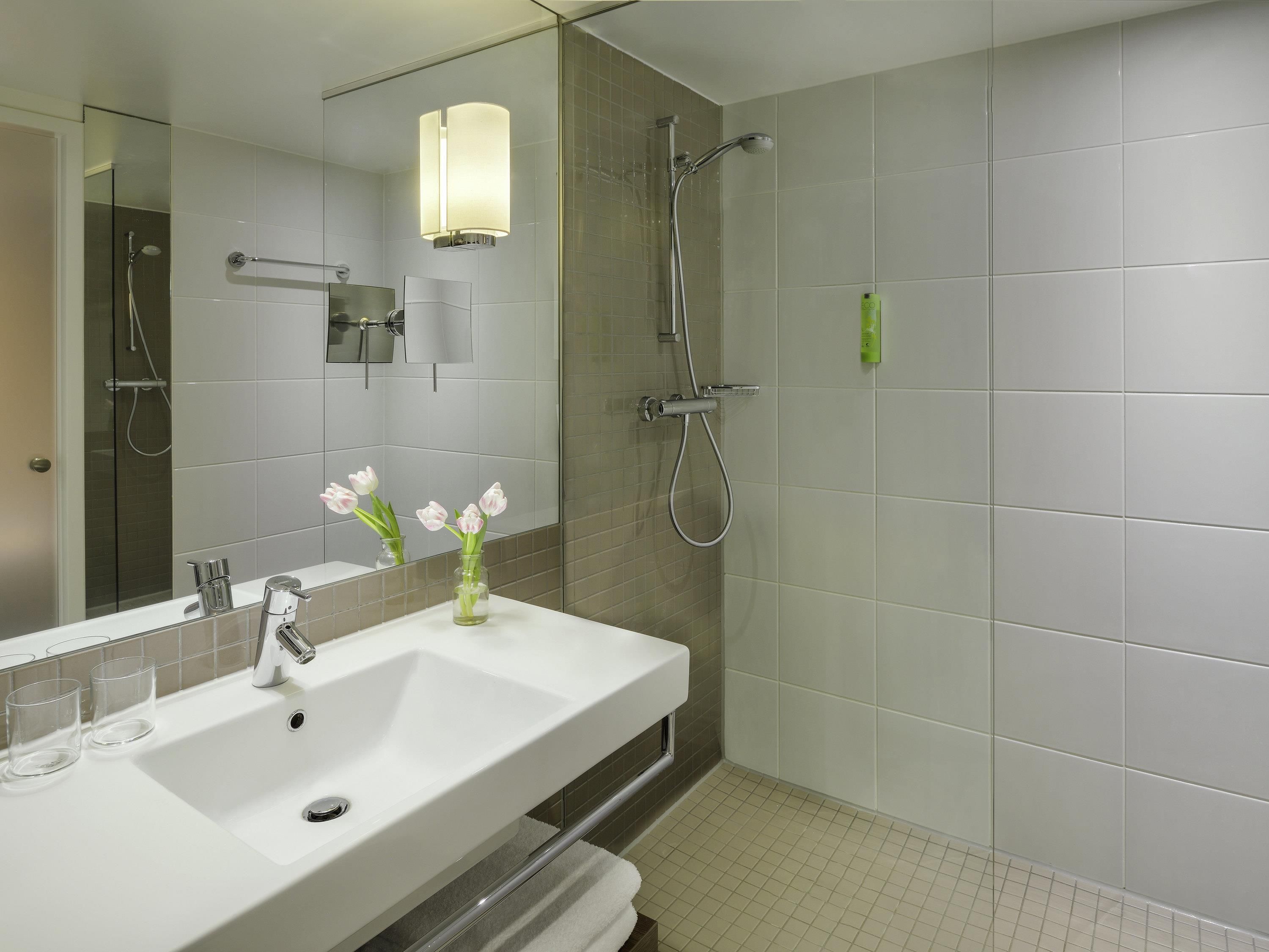 A bathroom with a white sink, mirror, and shower.