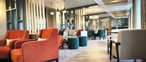 A modern lounge area with seating arrangements, wooden paneling, and pendant lighting.