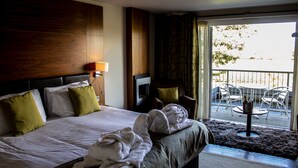 A hotel room with a large bed, a wooden headboard, a balcony with outdoor seating, and a view of trees. - Smiths at Gretna Green (Gretna)