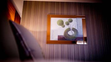 A framed artwork on a wall with vertical lines, a wooden floor, and a partial view of a white object.