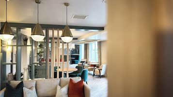 Una sala moderna con sofá, almohadones decorativos, lámparas colgantes y vistas al comedor.