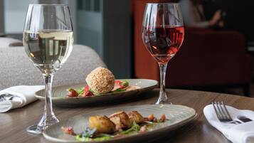 A dining table with two wine glasses, one with white wine and the other with red wine, and a plate of food.