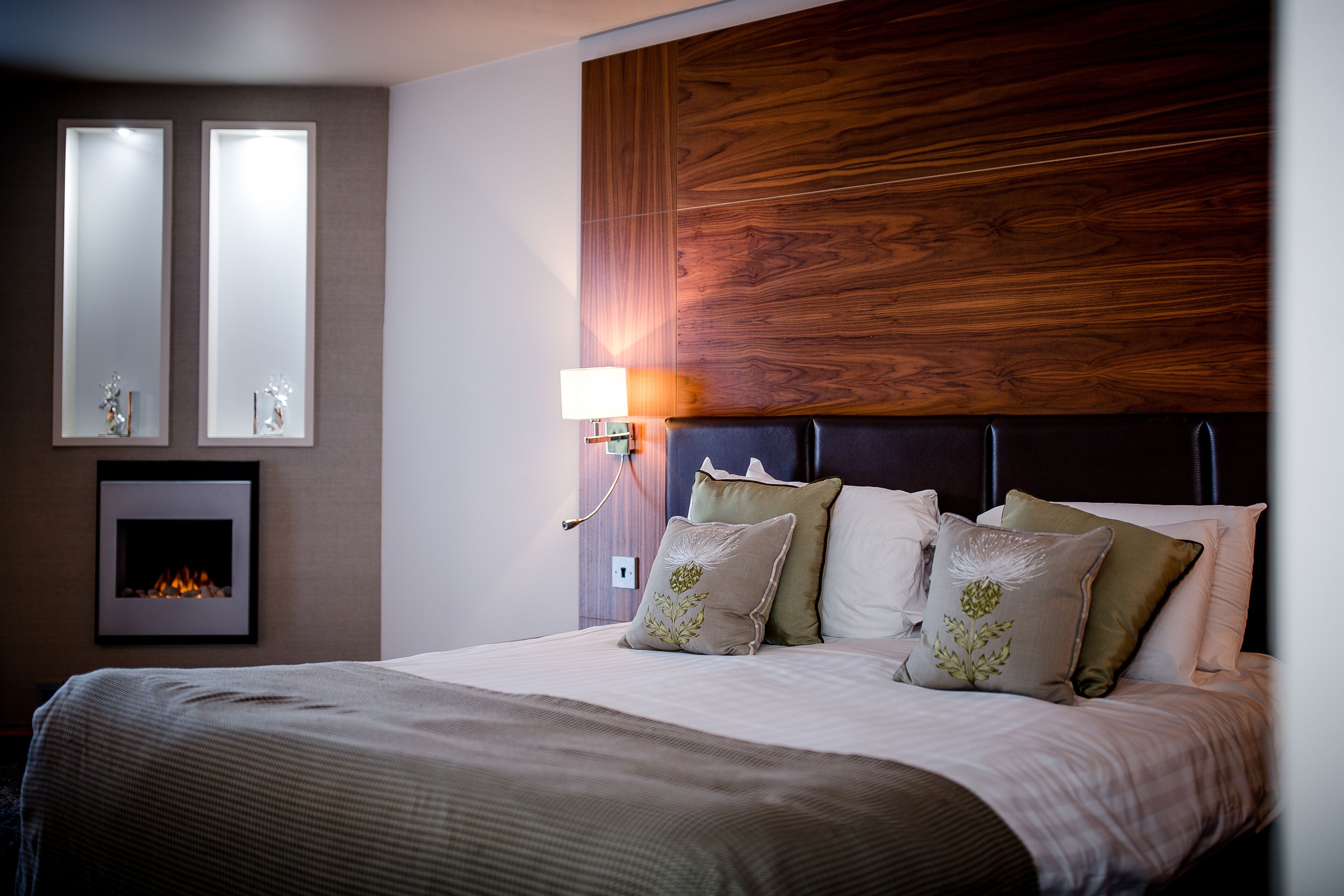 Een hotelkamer met een groot bed, een houten hoofdeinde, een wandspiegel en een open haard.